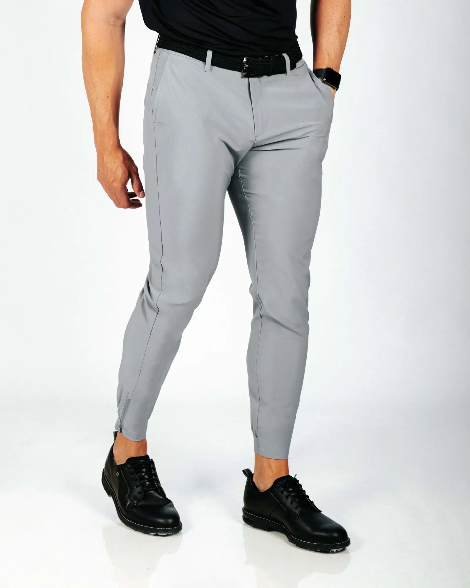 Person wearing gray pants and black shoes on a white background