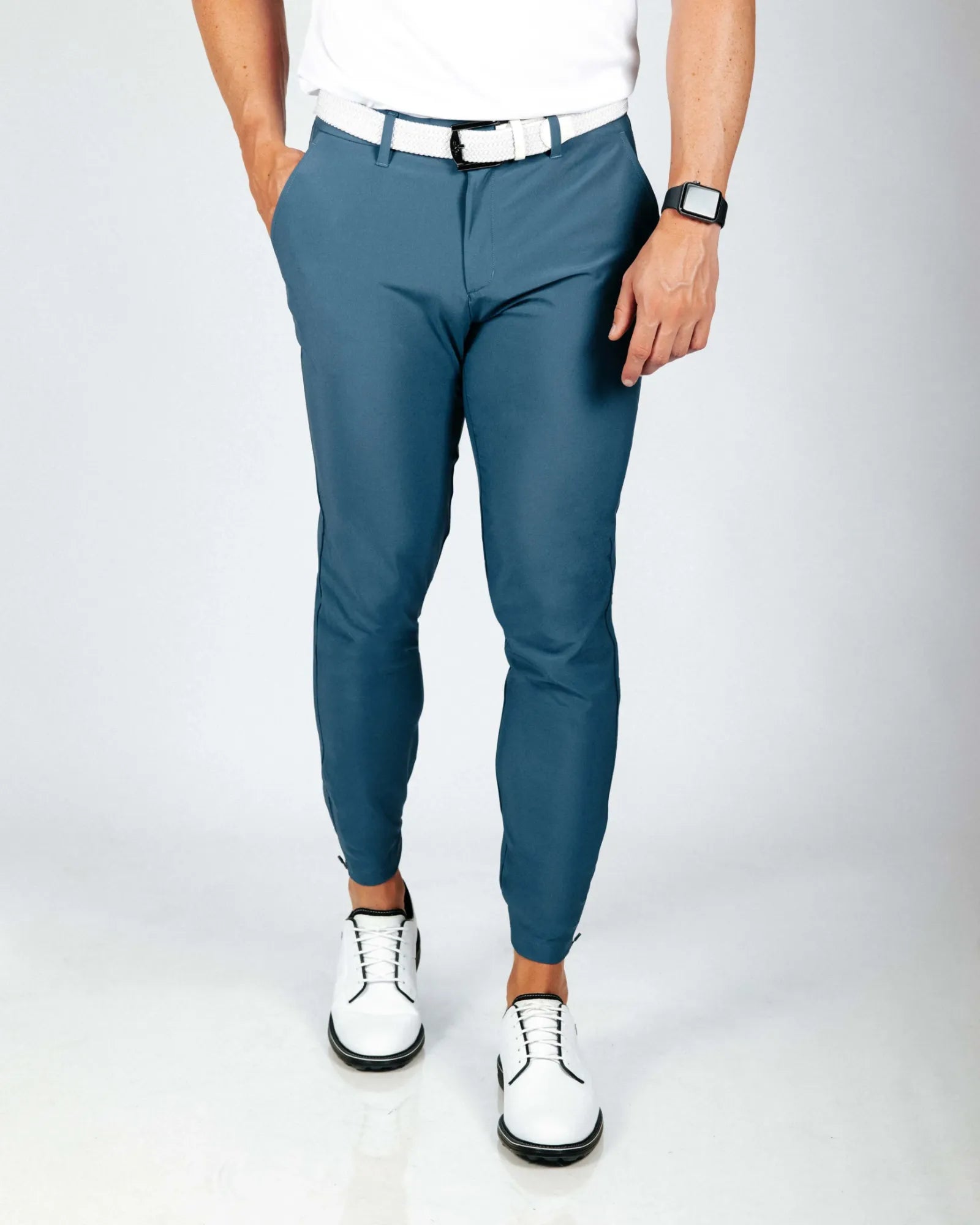 Person wearing blue pants and white shoes on a plain background