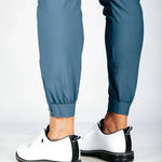 Person wearing blue pants and white sneakers with black soles on a light gray background