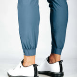 Person wearing blue pants and white sneakers with black soles on a light gray background