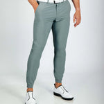 Person wearing smoke green golf pants and white shoes on a light gray background