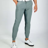 Person wearing smoke green golf pants and white shoes on a light gray background
