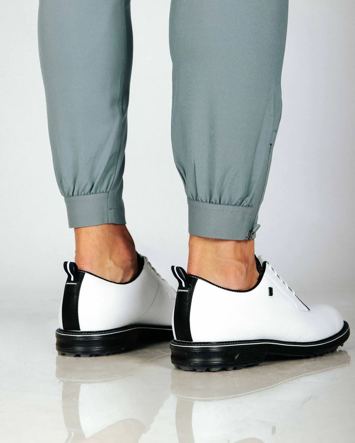 Close up of cuffed hem of pants with side zip. Model also wearing white golf shoes