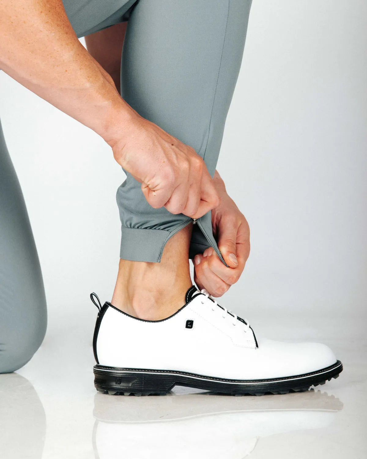 Person showing that there is a hem zip that gives options of how you want to wear them. Also makes them easy to get in and out of.  White shoes also featured in photo