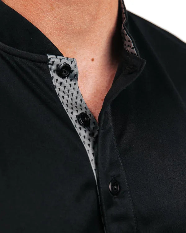 Close-up of a black polo with mock collar and patterned button placket.