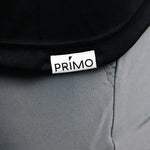Close-up of a black polo with a 'Primo' logo on gray pants.