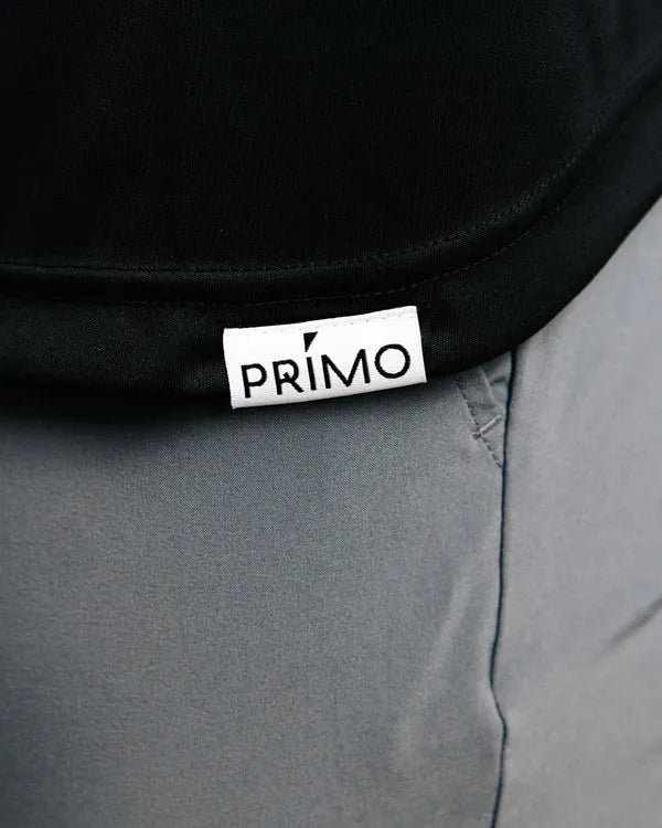 Close-up of a black polo with a 'Primo' logo on gray pants.