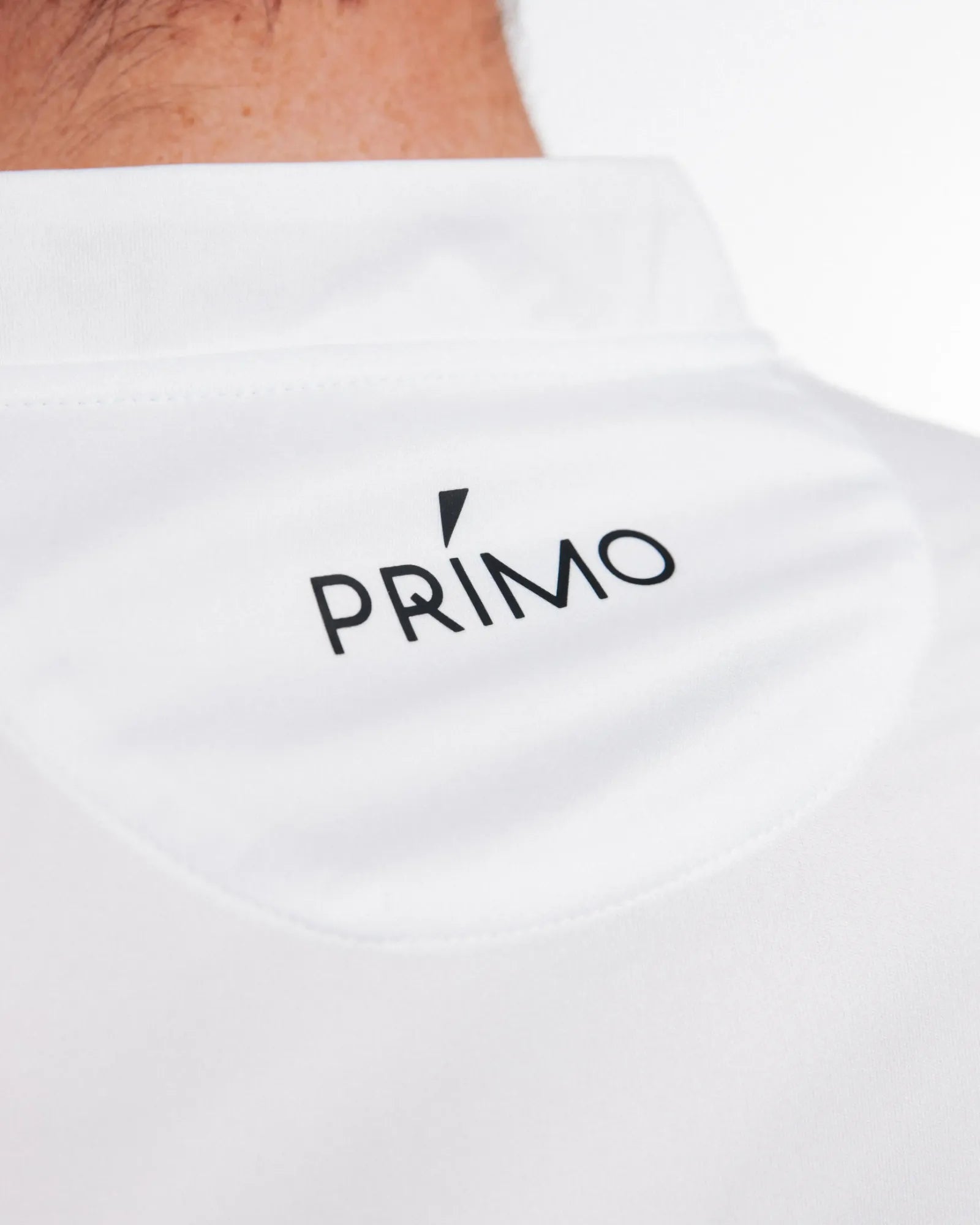 White golf polo with 'PRIMO' logo on the back