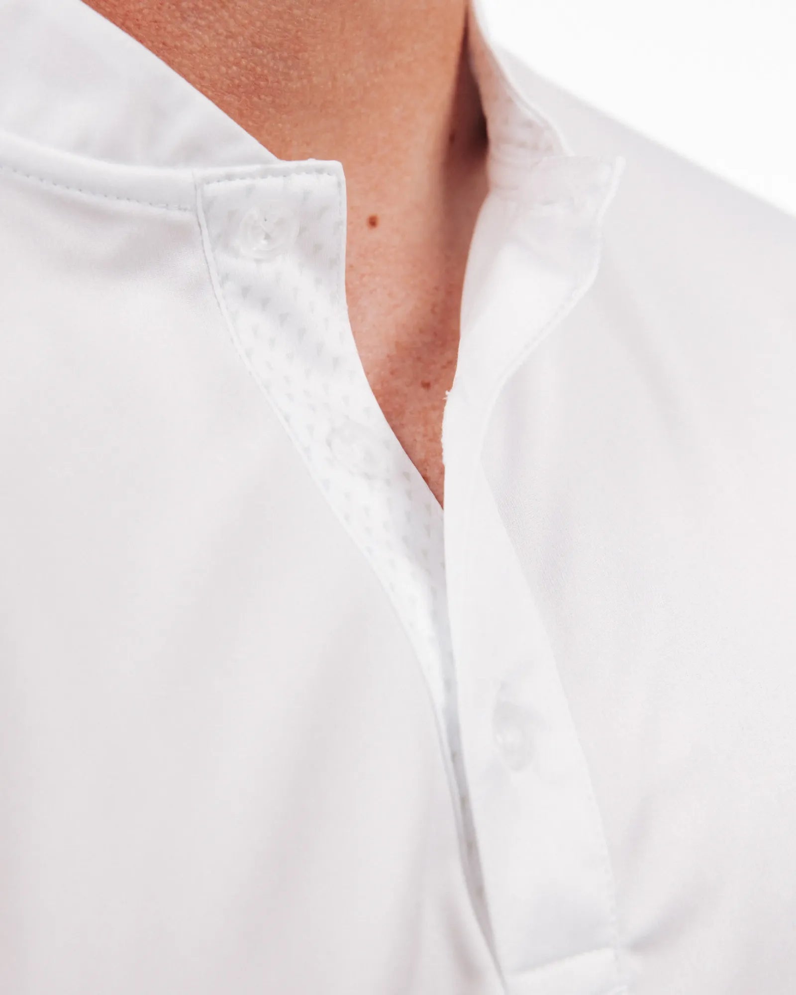 Close-up of a person wearing a white golf polo with a mock collar.