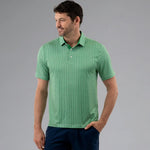 Man wearing a green patterned polo shirt against a gray background