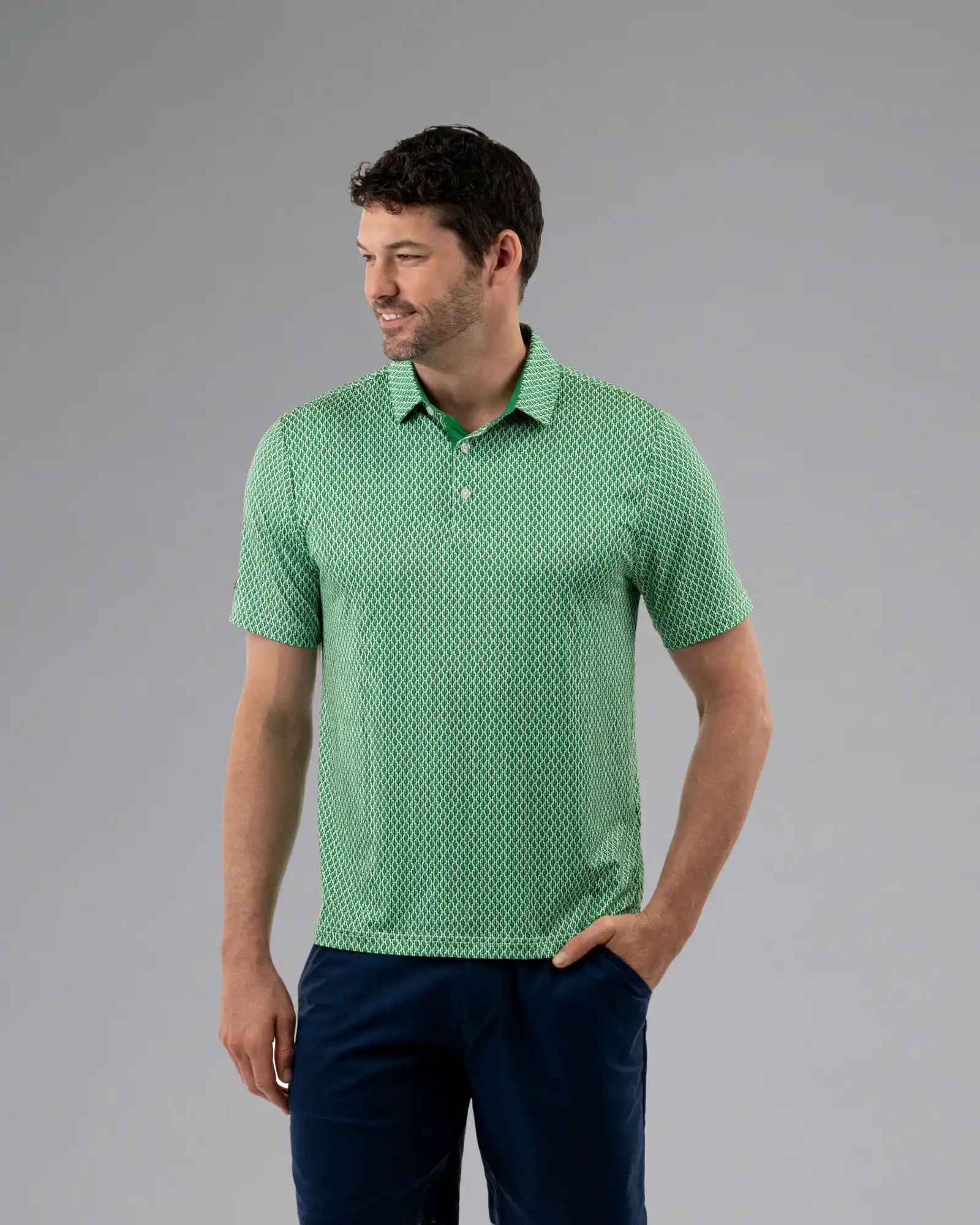 Man wearing a green patterned polo shirt against a gray background