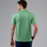 Man wearing a green patterned polo shirt on a gray background