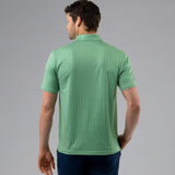 Man wearing a green patterned polo shirt on a gray background