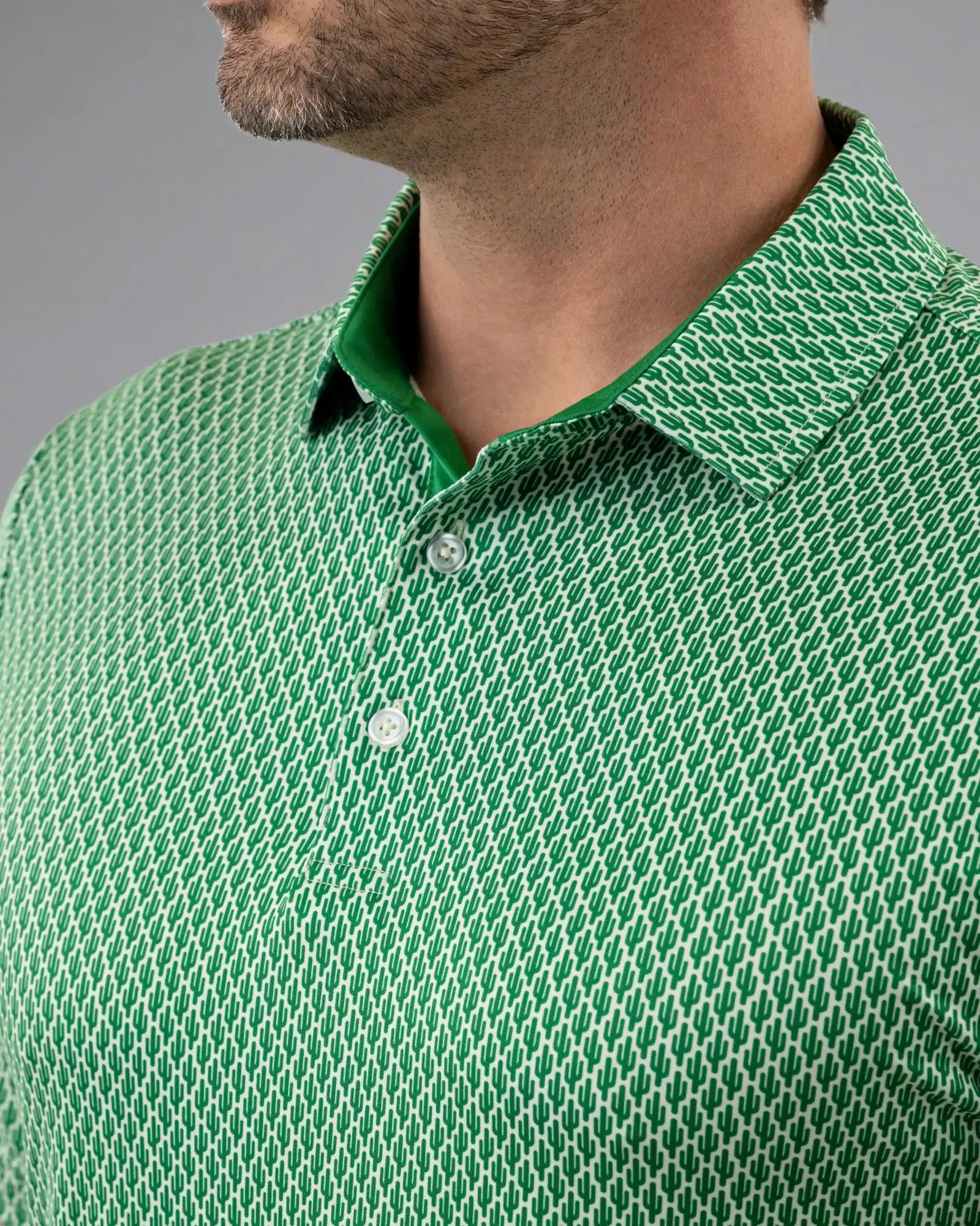 Close-up of a green patterned polo shirt with a gray background