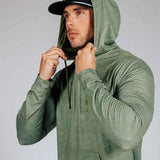 Man wearing green hoodie with hood on. Model is shown against a grey background