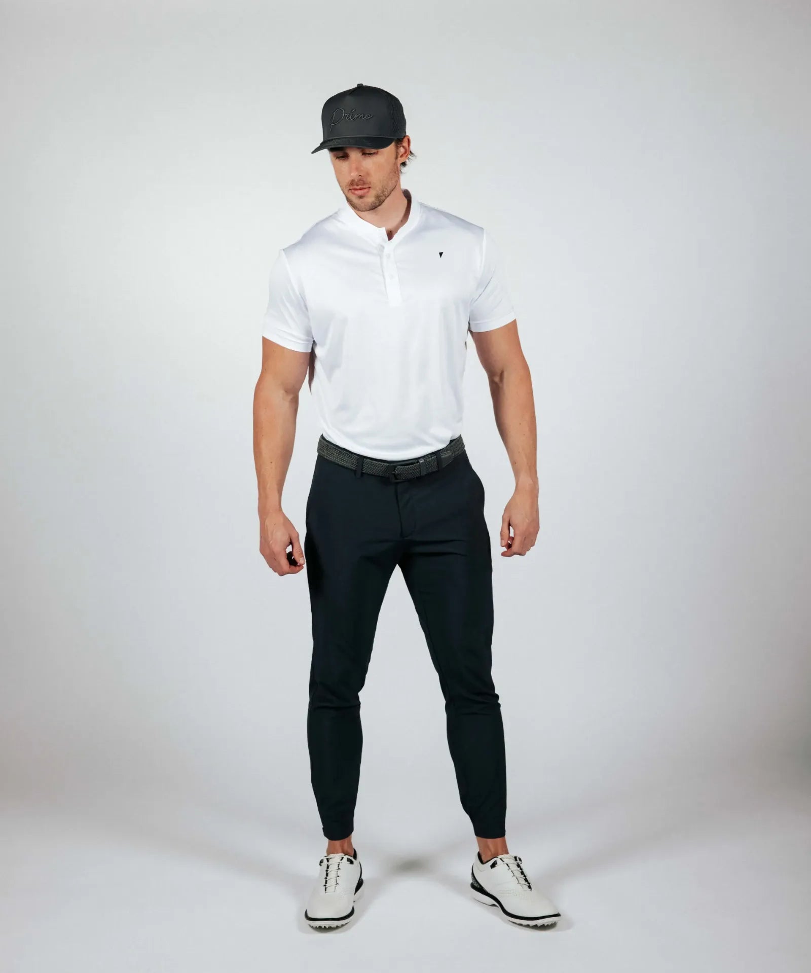 Man wearing a white polo shirt, black pants, and a cap on a white background