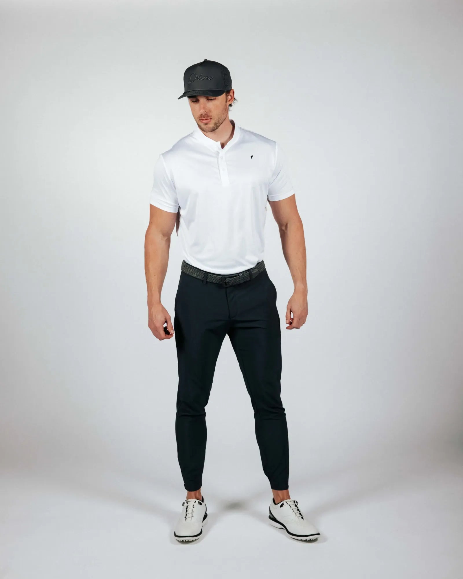 Man wearing a white polo shirt, black pants, and a cap on a white background