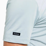 Light blue t-shirt with a brand logo on the sleeve against a white background