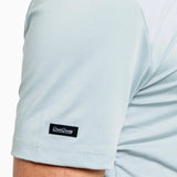Light blue t-shirt with a brand logo on the sleeve against a white background
