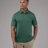 Man wearing a green polo shirt and beige pants against a gray background