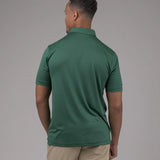Man wearing a green polo shirt and beige pants against a gray background