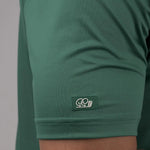 Green t-shirt with a brand logo on the sleeve against a neutral background