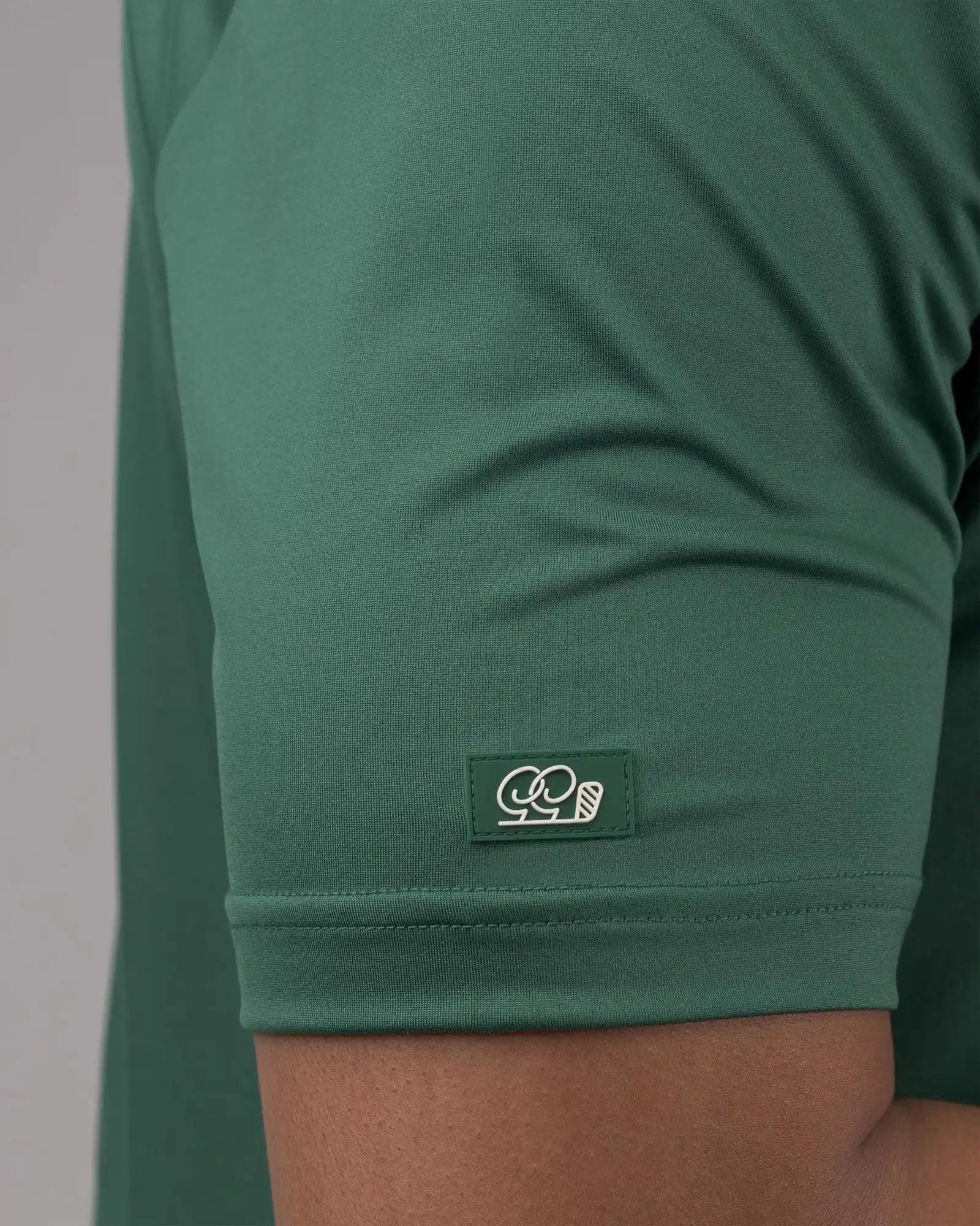 Green t-shirt with a brand logo on the sleeve against a neutral background
