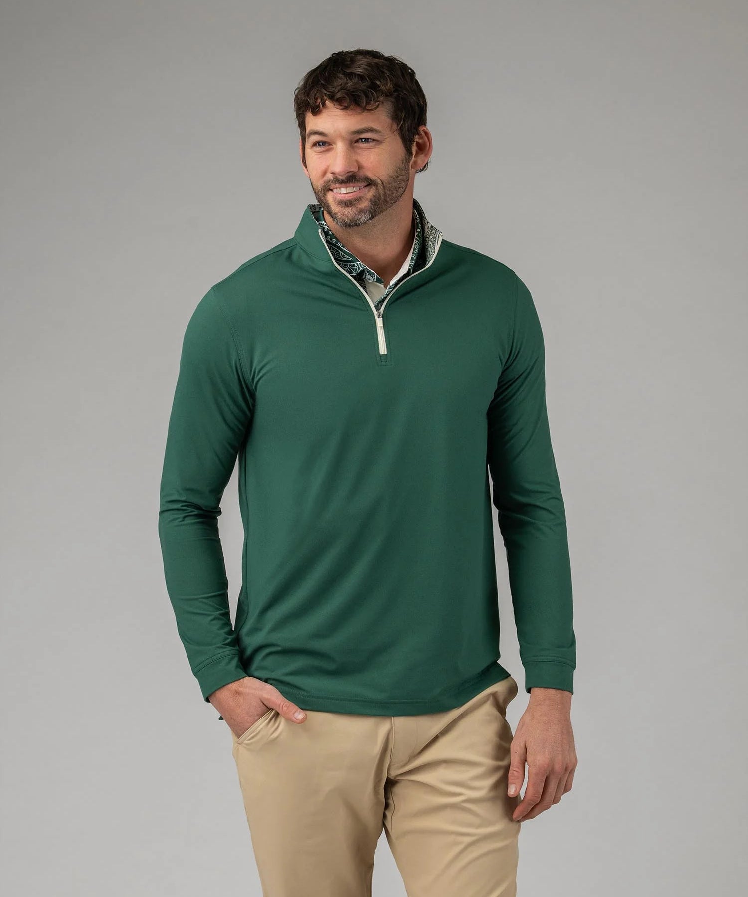 Man wearing a green long-sleeve shirt with a white collar against a gray background