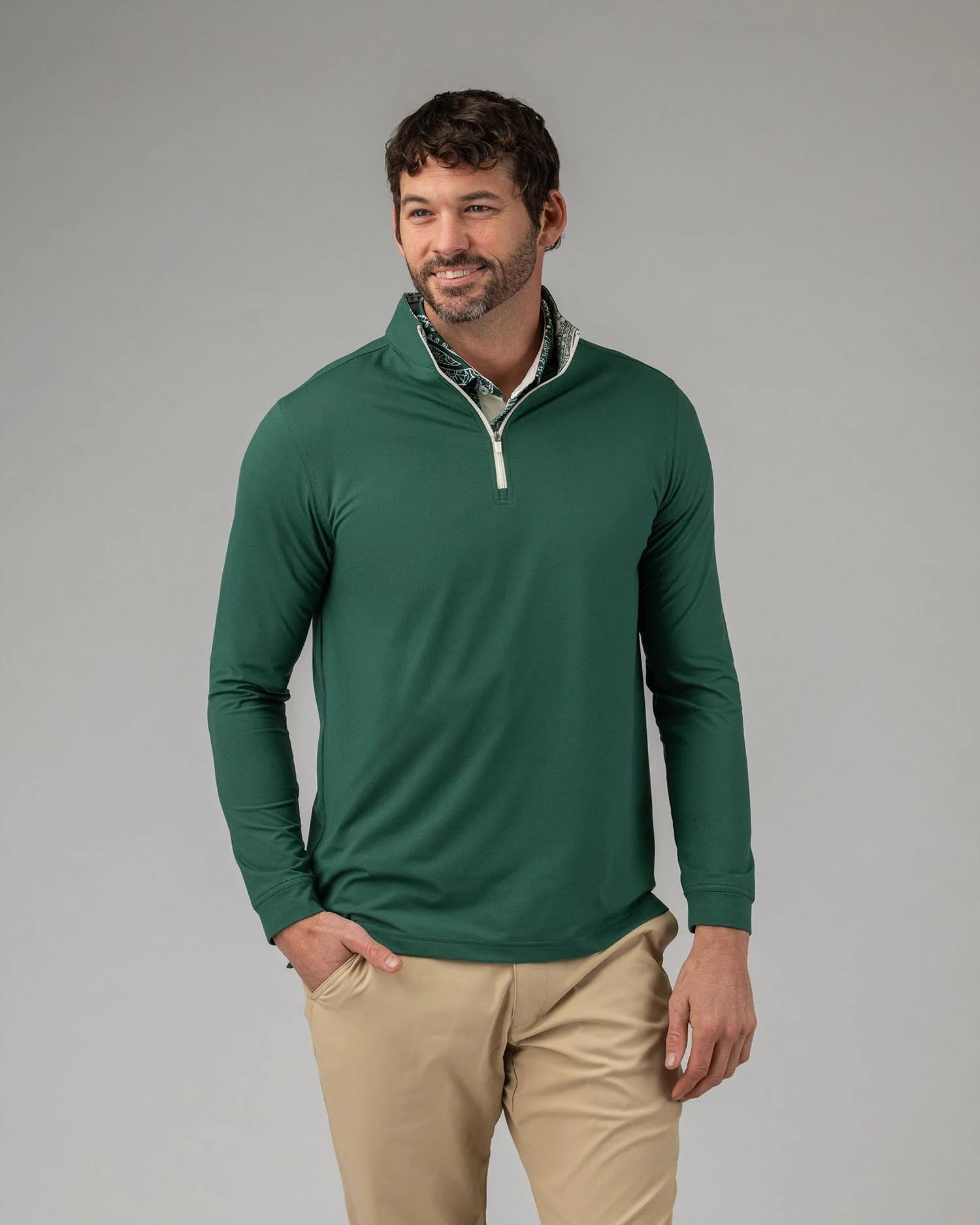 Man wearing a green long-sleeve shirt with a white collar against a gray background