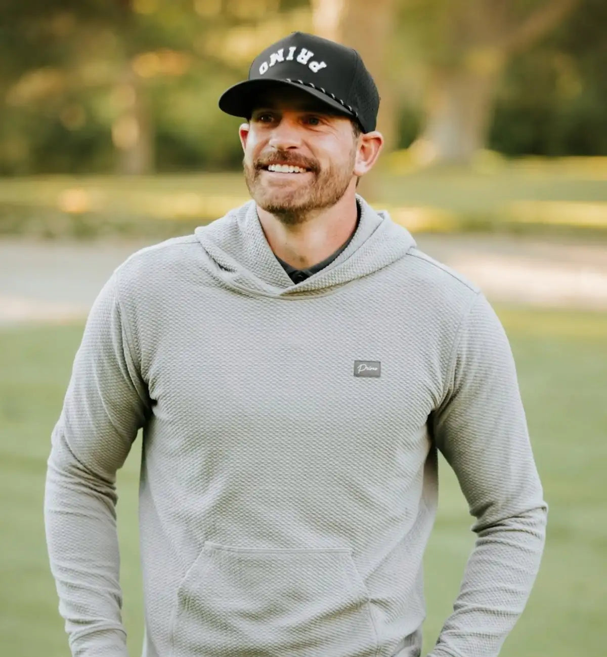 Man wearing a gray hoodie and black cap outdoors