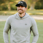Man wearing a gray hoodie and black cap outdoors