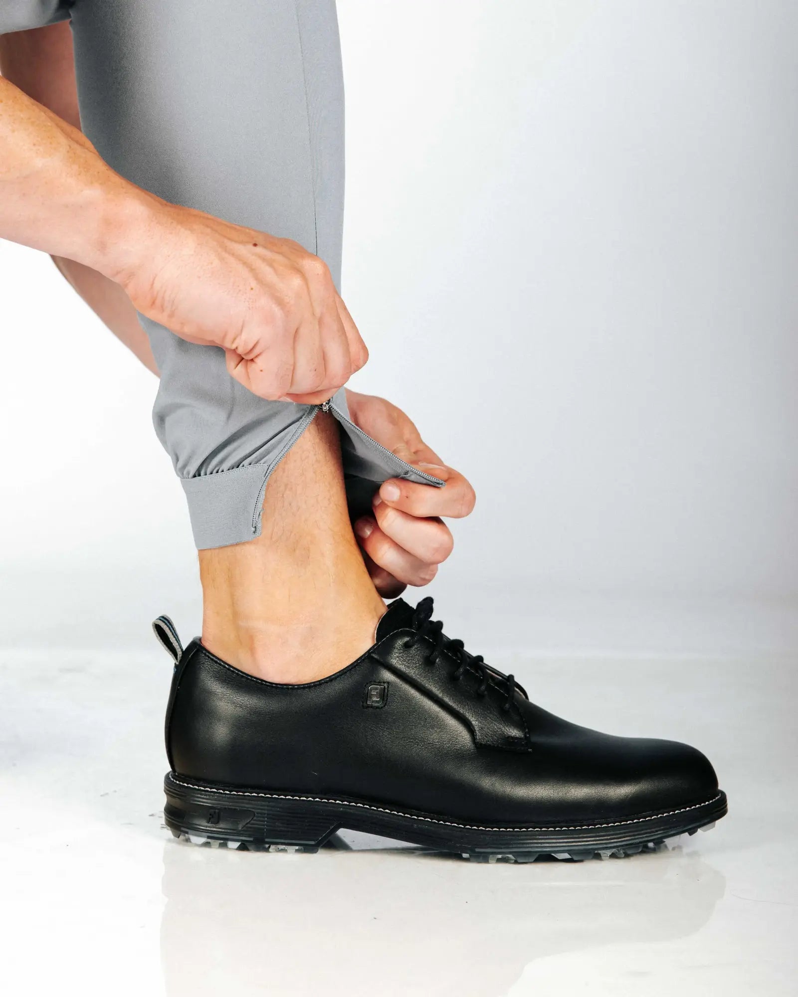 Person showing off hem zip for easy access. Also wearing black shoes.