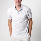 Man wearing a white polo shirt with a logo on a plain background