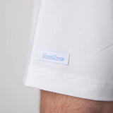 Close-up of a white shirt with a blue logo on a light gray background